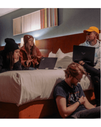 Students from Arizona team gathered together on a hotel bed to study. Two students have laptops.