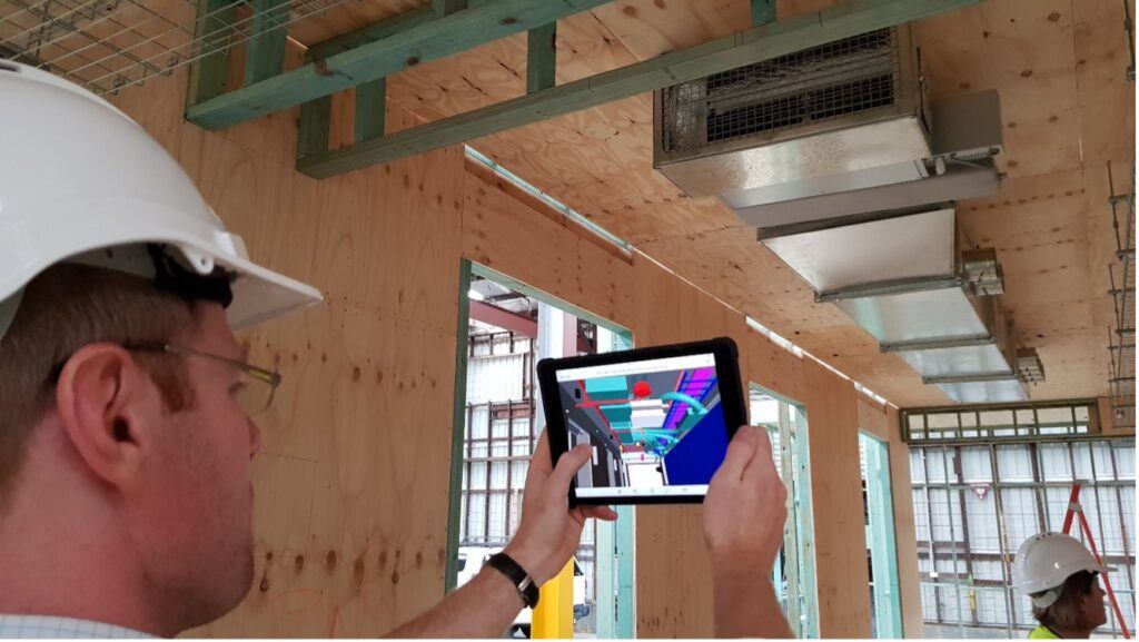 Male construction team member holds tablet with digital rendering in front of him to compare results with the digital plan