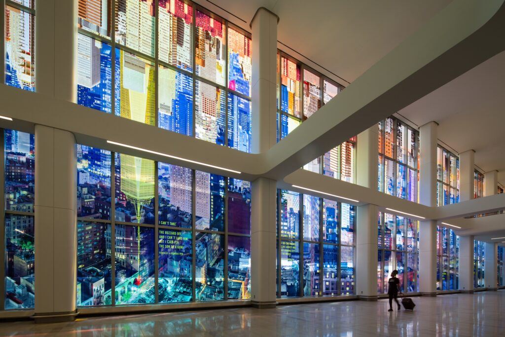 Interior of new Terminal B at LaGuardia Airport: mural in large windows with one passenger walking by with suitcase on wheels