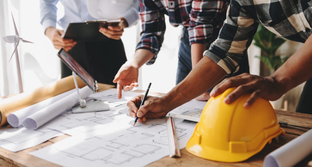 Engineer teams meeting working together wear worker helmets hardhat on construction site in modern city.