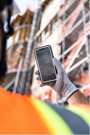 Construction worker holding phone with Revizto Site app